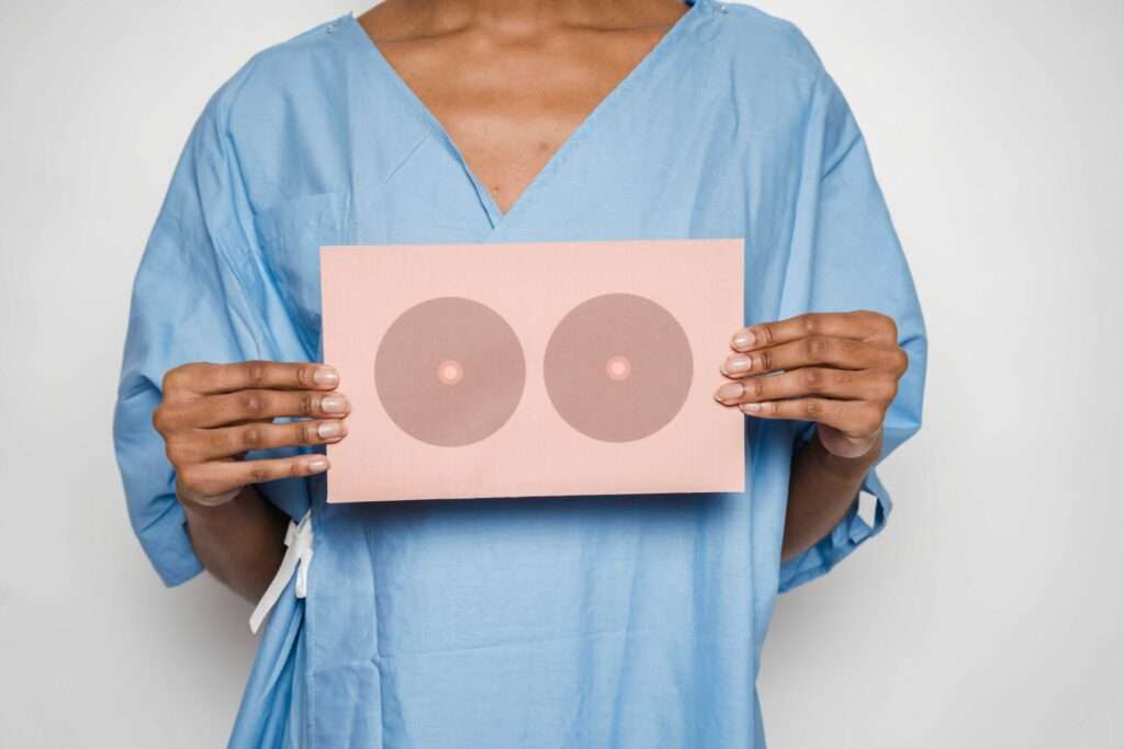 kobieta trzymająca kartkę przed klatką piersiową z narysowanymi piersiami - BRCA1 BRCA2 rak piersi